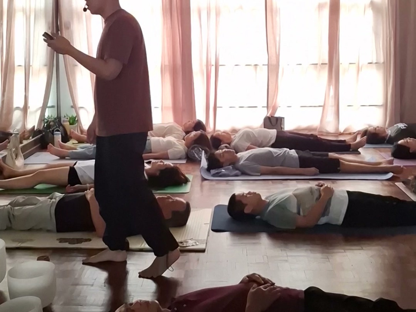 A room of participants lying on mats with hands on the belly while Hong guides a breathwork session in Malaysia