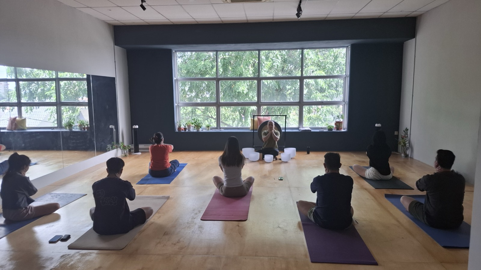 Hong leading a workplace team through seated breathing techniques in a training room