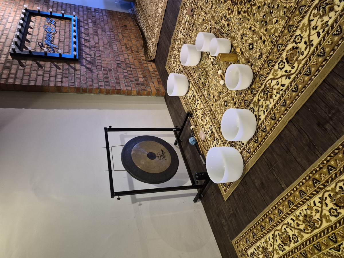 Crystal singing bowls, gong and mallets laid out on a rug before a session