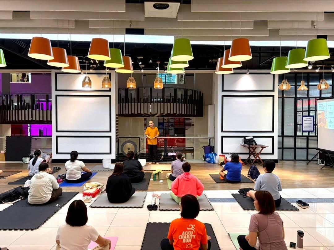 A group seated on mats listening to Hong during a group breathwork session