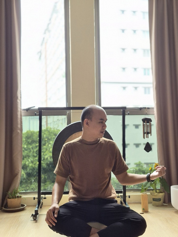 Hong seated by a window during a one-to-one breathwork session